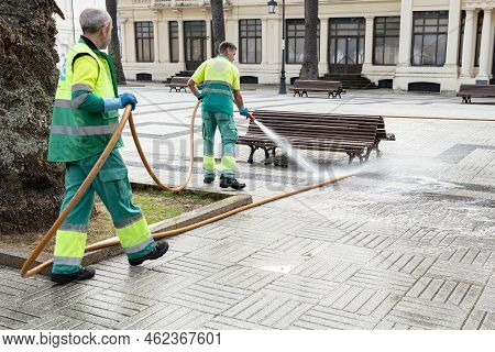 La Coruna, Spain; September 23, 2022: Two Workers Cleaning A City Square With Water Using A Hosepipe