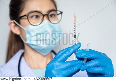Asian Healthcare Worker Holding And Looking To A Syringe Before Inject Or Take Out Fluid. A Syringe 