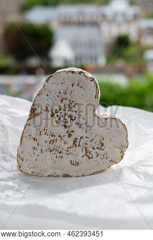 French Heartshaped Neufchatel Cow Cheese On White Paper And View On Old Houses Of Etretat, Normandy,