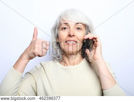 Modern Lifestyle, Tehnology And Old People Concept: Photo Of Old Woman Use Smartphone And Show Thumb