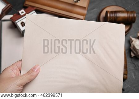 Woman Holding Last Will And Testament At Grey Table, Closeup