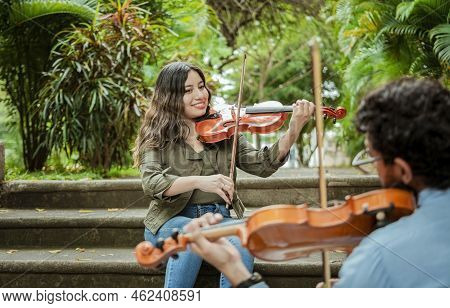 Portrait Of Violinist People Sitting On Stairs Playing Violin. Portrait Of Two Young Violists Playin