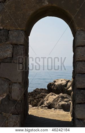 Arco antiguo con el mar y las rocas en Cefalu