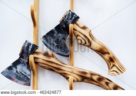 Metal Axes With A Wooden Handle On A White Wall Background. Manufacture And Sale Of Handmade Steel T