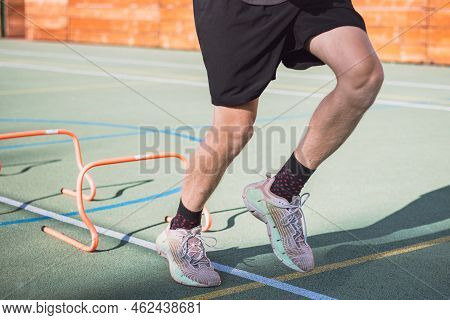 Blond Boy In Sportswear Jumps Over Red Obstacles To Improve Lower Body Dynamics. Plyometric Training