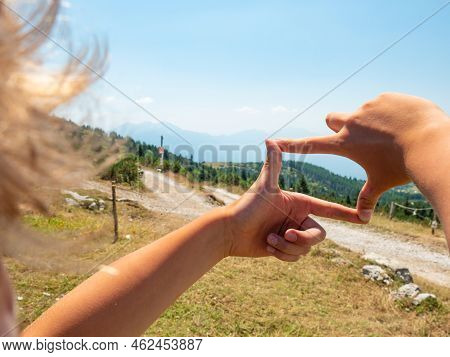 Blond Hair Boy Is Framing By Fingers Wooden Tourist Sign At Gravel Road To Hill Peak. Enjoy Trek And