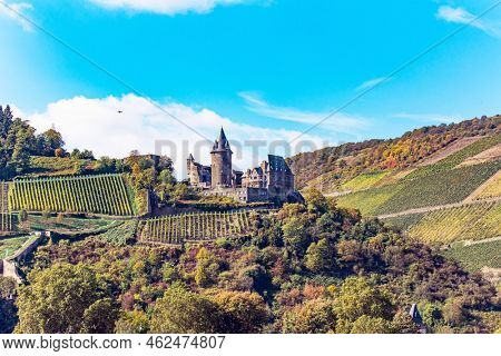  Medieval knight's castles and ruins. Castle Stahleck stands on a ledge of a mountain slope. Warm autumn in Germany. Beautiful wooded slopes of the coastal hills of the river Rhine.  