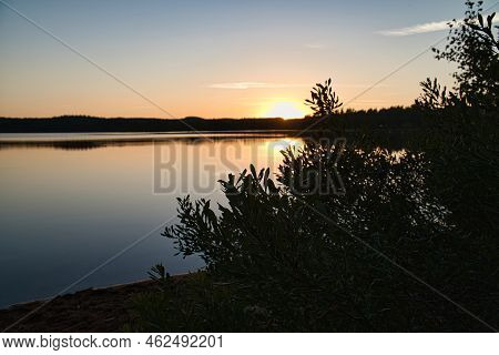 Sunset With Reflection On A Swedish Lake In Smalland With Bushes In The Foreground On The Shore. Rom
