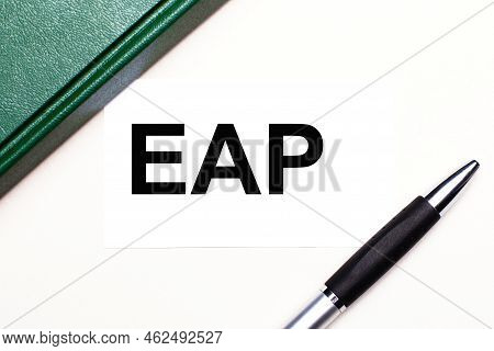 On A Light Gray Background Lies A Pen, A Green Notebook And A White Card With The Text Eap Employee 