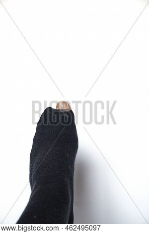 Hole In A Black Sock Through Which The Big Toe Sticks Out. White Background. Upright Image. Copyspac