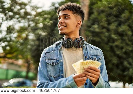 Hispanic young man holding 100 danish krone baknotes at the university campus