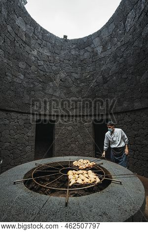 Cook Grilling Chicken On Volcanic Heat In El Diablo Restaurant, Spain