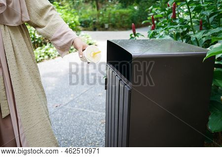 Women Hand Throwing An Empty Plastic Water Bottle In The Garbage Trash Or Bin