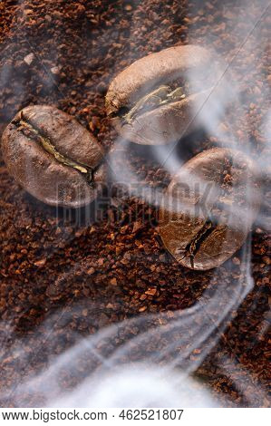 Three Coffee Beans Lie On Ground Coffee, Light Aromatic Coffee Smoke.