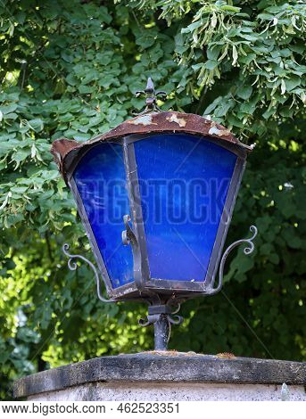 A Lantern With Blue Discson A Gatepost.
