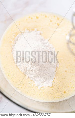 Mixing Ingredients In A Large Glass Mixing Bowl To Bake Apple Sharlotka Muffin.