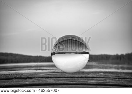 Glass Ball On A Wooden Pier At A Swedish Lake At Dusk In Black And White. Nature Shot From Scandinav