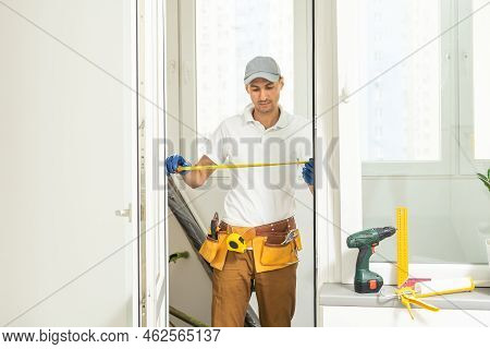 A Repairman Repairs, Adjusts Or Installs Metal-plastic Windows In The Apartment. Glazing Of Balconie