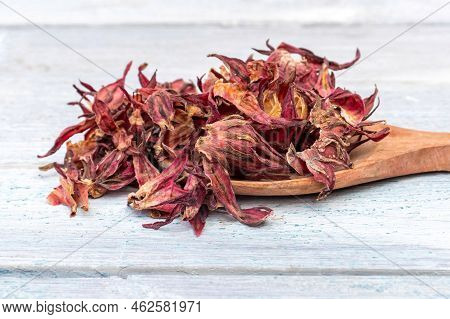 Closeup Of Dreid Roselle Fruit Or Hibiscus Sabdariffa Fruit In Wooden Ladle Isolated On White Wooden