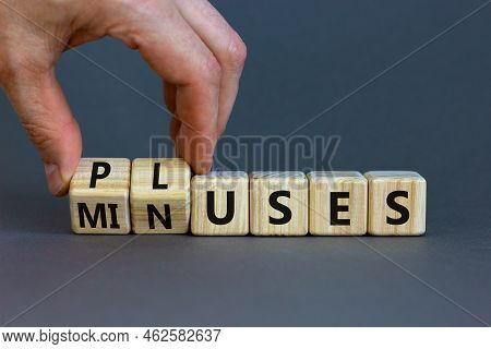 Pluses And Minuses Symbol. Businessman Turns Wooden Cubes And Changes The Word 'minuses' To 'pluses'