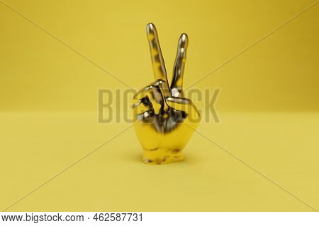 A Symbol Of Victory. Victory Hand Of Gold Color On A Yellow Background. 3d Render.