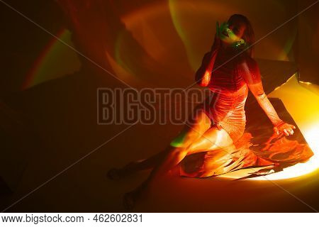 Glamorous Portrait Of A Young Beautiful Blonde In A Stylish Scarlet Short Dress, Sitting On The Floo