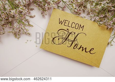 Welcome Home Written On Paper Card With Flower Frame Decoraton On Pink Background