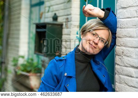 Portrait Of An Attractive Thirty Year Old White Woman Posing At A Traditional White And Green Facade
