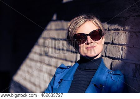Portrait Of An Attractive Thirty Year Old White Woman Posing Against A Rough Brick Wall With A Hard 