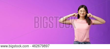 Displeased Annoyed Asian Brunette Woman Fed Up Hearing Loud Parents Yell, Close Eyes Grimacing, Plug