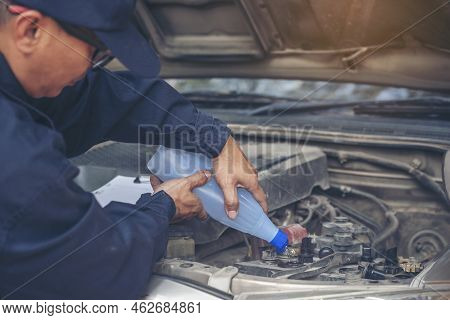 Car Mechanic Man Hands Pouring Deionized Purified Distilled Water For Car Battery Mechanical Service