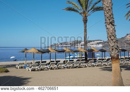 Umbrellas And Sun Loungers On The Beach Of Almuñecar Bathed By The Water Of The Mediterranean Sea, S