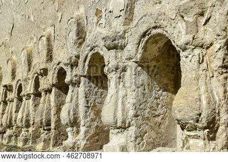 Stone Relief Columns Carved In The Wall. Texture Of Old Dilapidated Masonry. Ancient Half-ruined Syn
