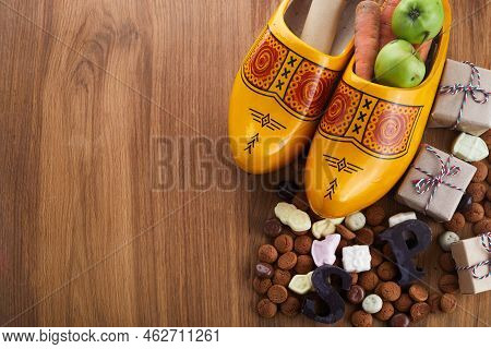 Saint Nicholas - Sinterklaas Day With Shoe, Carrot And Traditional Sweets On Wooden Background