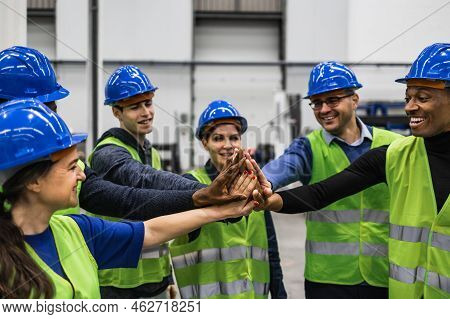 Team Of Multiracial Engineers Stacking Hands Together Inside Robotic Factory - Tech Industry Concept