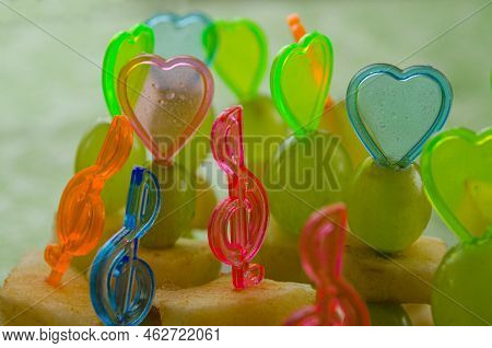 Canape From Banana, Grape And Apple. Fruit Sandwiches With Colored Hearts On A Plate On A Green Tabl