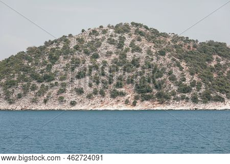 Small Greek Island Covered With Small Vegetation During A Sunny Summer Day.