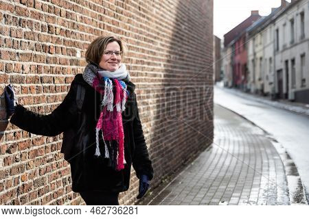 Attractive Thirty Year Old Woman Posing Against A Brick Wall In The Streets Of Old Town, Jodoigne, B