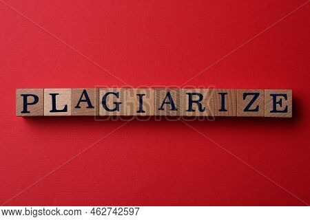 Wooden Cubes With Word Plagiarism On Red Background, Flat Lay