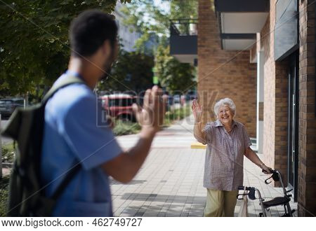 Caregiver Saying Goodbye His Senior Woman Client At Nursing Home.
