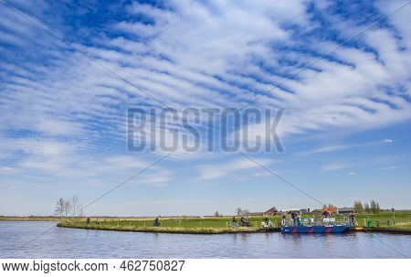 Eernewoude, Netherlands - April 27, 2021: People Taking The Bicycle Ferry To Cross The River In Frie