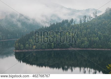 Rainy And Foggy Morning At The Sance Dam. Reflection Of Deciduous Forest On The Water Surface. Autum