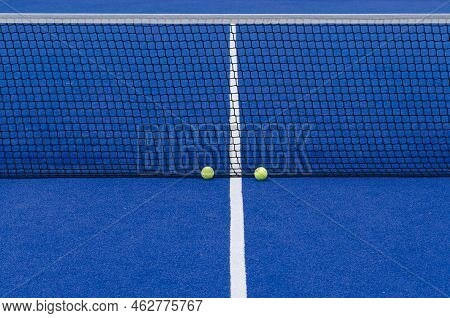 Two Balls At The Net Of A Paddle Tennis Court