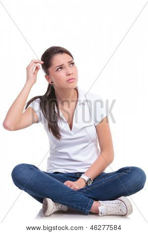 Casual jonge vrouw zitten met de benen gekruist en opzoeken van verward. geïsoleerd op witte achtergrond