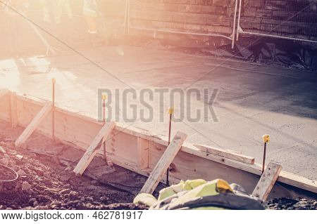 Builders Pouring Concrete Slab With Help Of A Concrete Pump And Using Vibrating Poker To Compact Wet