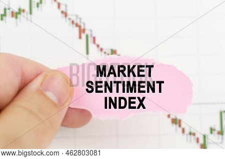 Business And Trading Concept. Against The Background Of The Quote Chart, A Man Holds A Sign With The