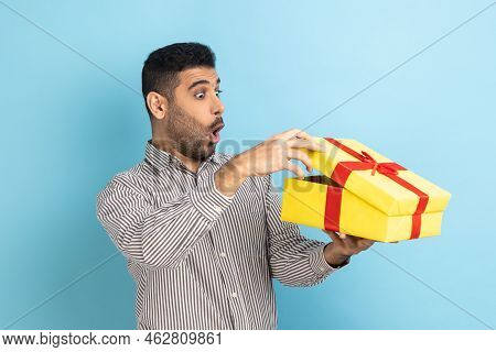 Portrait Of Surprised Curious Businessman Looking Into Gift Box, Opening Present And Peeking Inside 