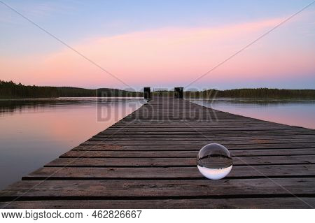 Glass Ball On A Wooden Pier At A Swedish Lake At Evening Hour. Nature Shot From Scandinavia