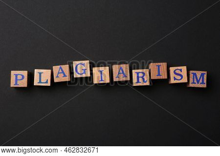 Wooden Cubes With Word Plagiarism On Black Background, Flat Lay