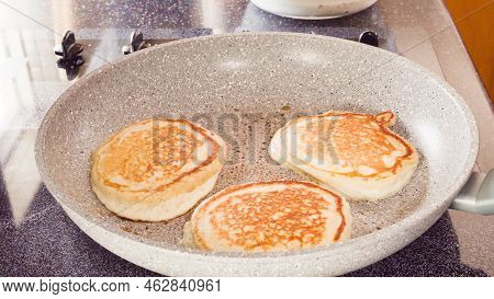 Frying Pancakes In A Frying Pan Over The Electric Stove.